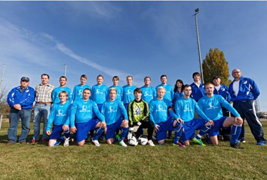 Ein Fußballteam posiert in zwei Reihen auf einem Fußballfeld.