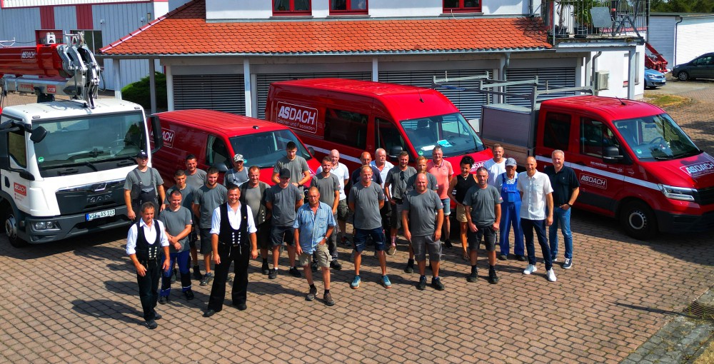 Dronenbild des ASDACH Teams, das lächelnd vor den Einsatzfahrzeugen steht.